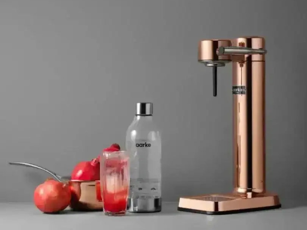 Aarke III copper water carbonator with a PET bottle, fresh apples and a sparkling fruit drink
