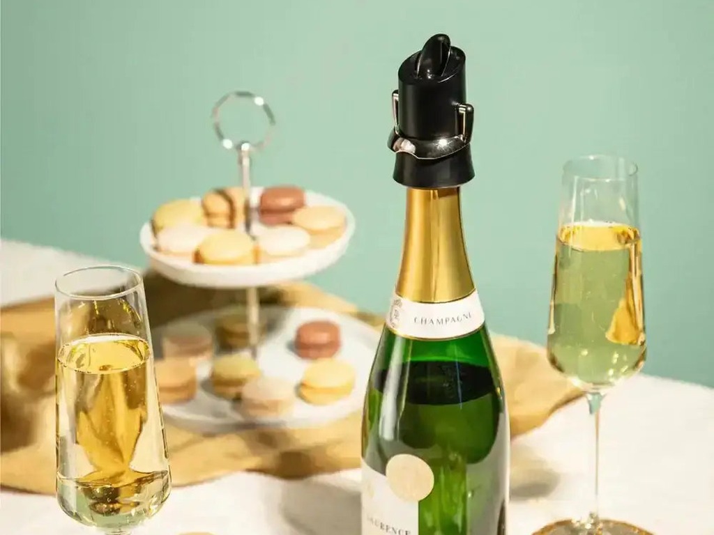 Vacu Vin champagne server and saver fitted to an open champagne bottle beside filled flutes and macarons