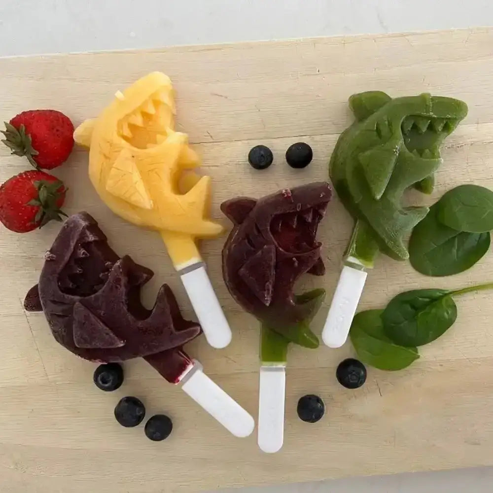 Colourful home-made Zoku shark ice pops arranged with strawberries, blueberries and spinach