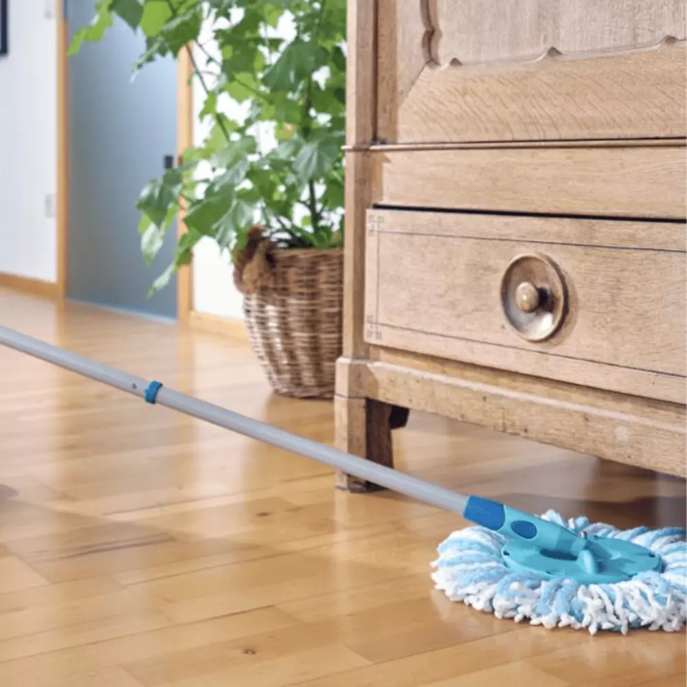 A blue and white microfibre spray mop cleaning a wooden kitchen floor