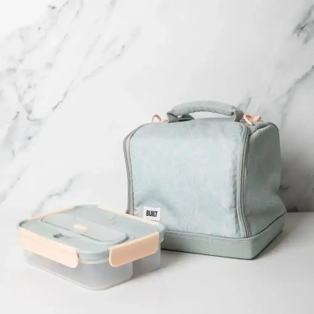 A Built Bowery insulated lunch bag in soft mint beside a matching lunch box on marble