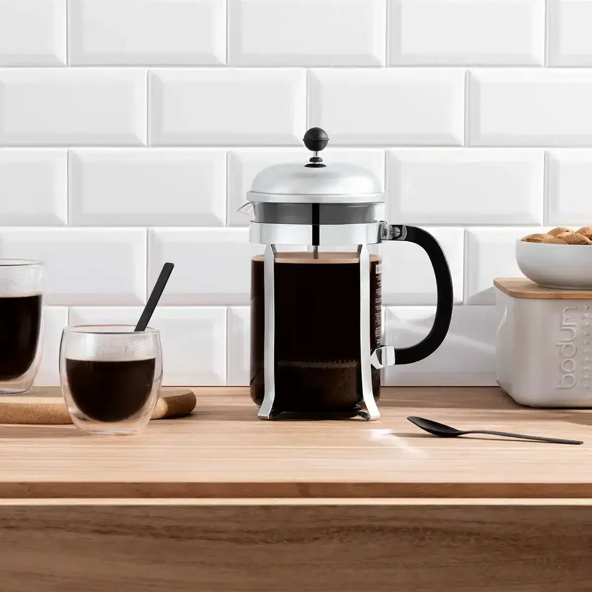 A stainless steel Bodum French press on a wooden counter with freshly brewed coffee