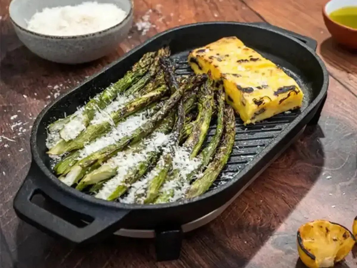 Chargrilled asparagus and polenta on a ridged cast-iron grill pan on a warm timber table