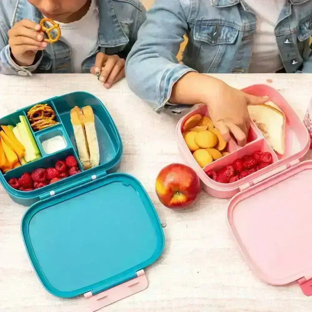A child reaching into an open compartment lunch box filled with fruit, crackers and vegetables on a pale table