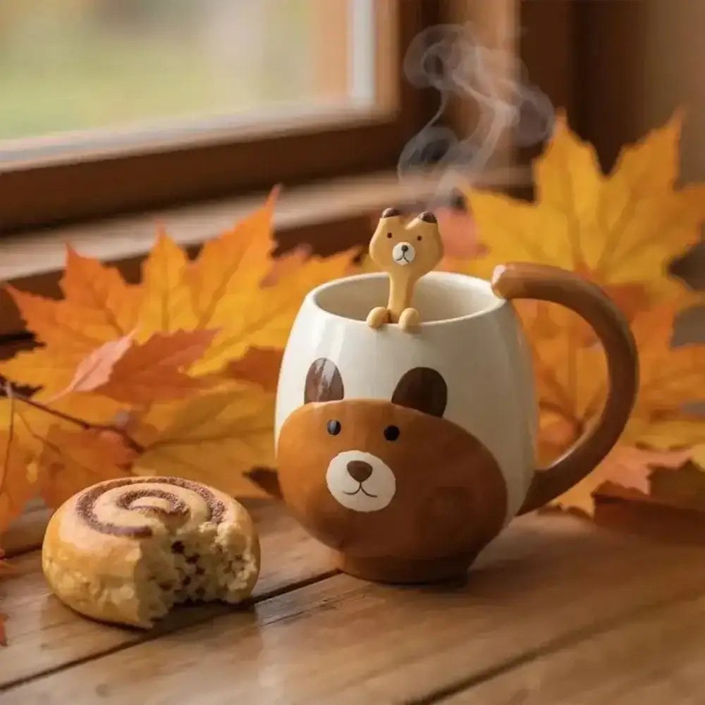 A Nicolson Russell Brush & Barrow bear mug with its matching spoon on a timber window sill beside a cinnamon bun