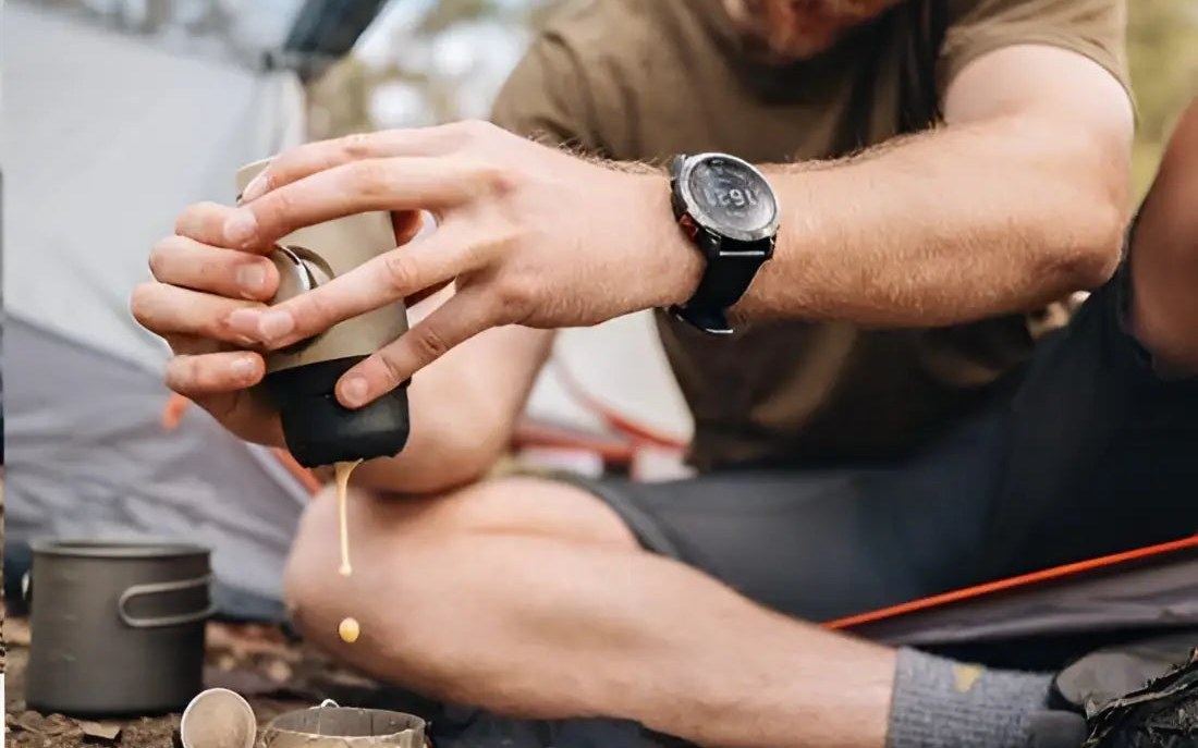 A man brewing espresso with a Wacaco Minipresso beside a tent