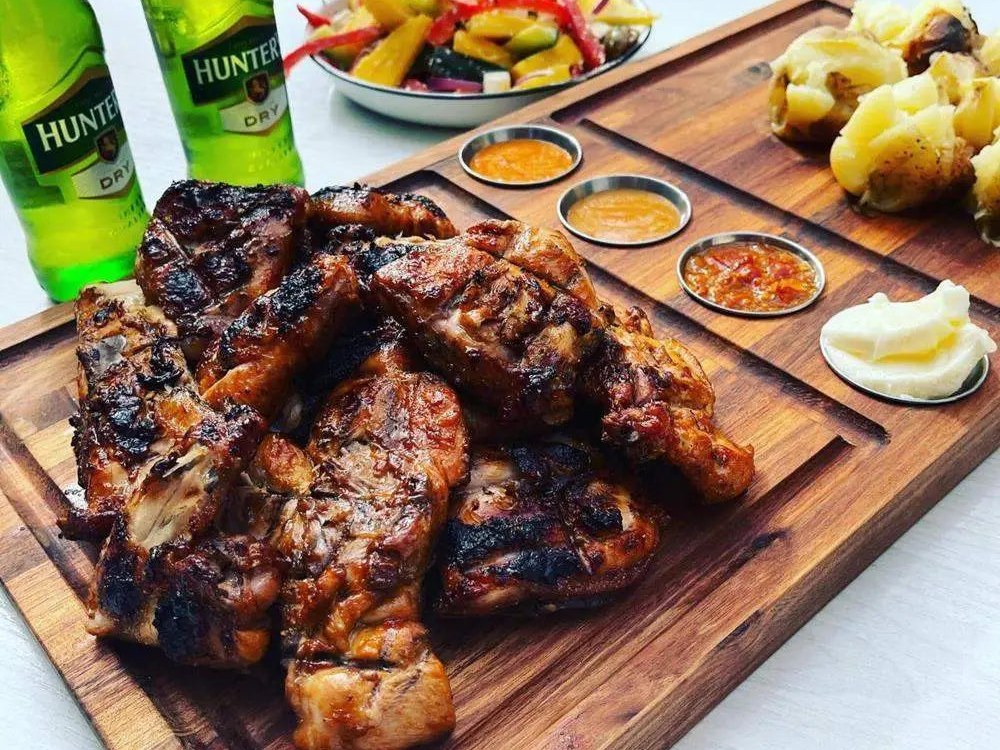 Grilled chicken and sauces on a My Butchers Block teak meat serving board with cold drinks alongside