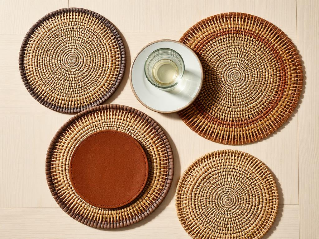 Woven placemats and a leather coaster on a light wooden table